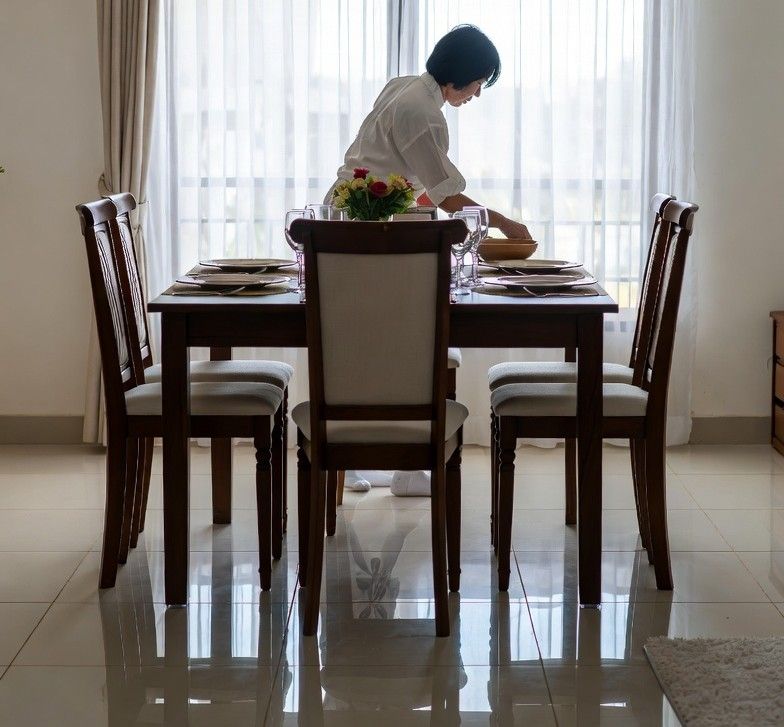 homeowner preparing a dining table with clean, shiny tiled floors in the foreground